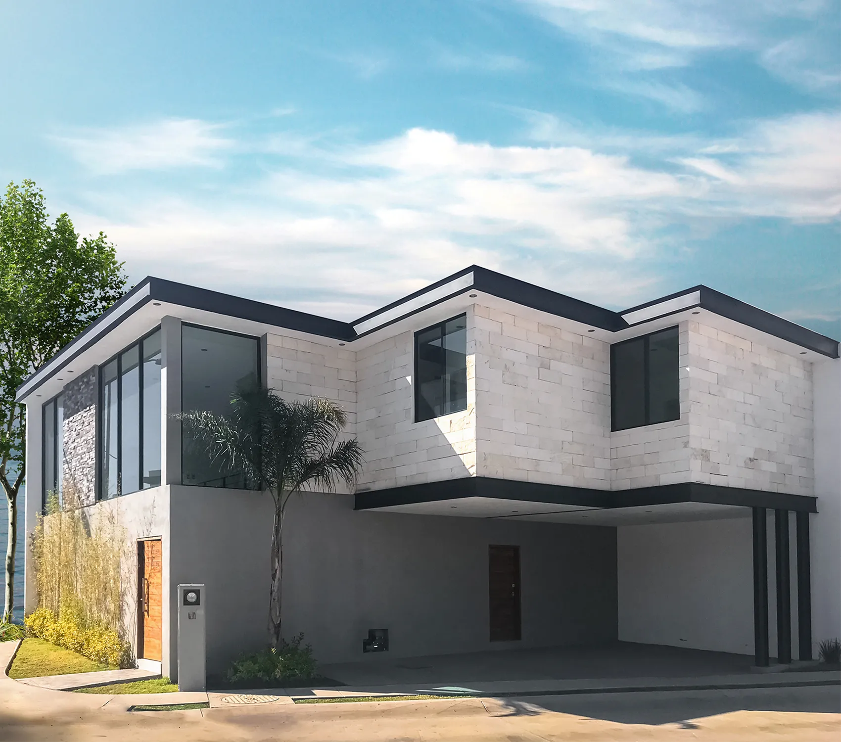 Fachada residencial moderna en formato vertical: volumen superior revestido de piedra blanca Galarza en voladizo sobre cochera abierta y detalles en acero negro.